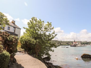 A riverside path next to a house with boats on the water at Ynys Faelog Cottage in Ynys Faelog near Menai Bridge