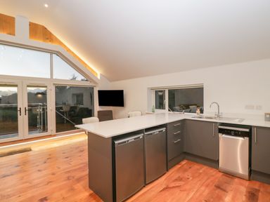 A kitchen with a white countertop and grey cabinets with two small refrigerators and a dishwasher by Upper Annex in Quemerford