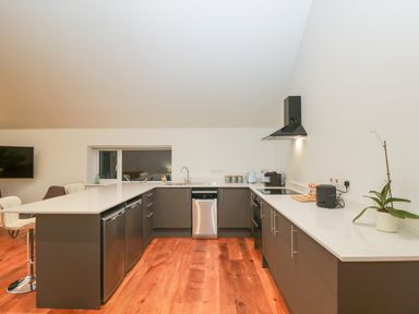 A kitchen with dark cabinets a white countertop a sink dishwasher stove and bar stools at Upper Annex in Quemerford