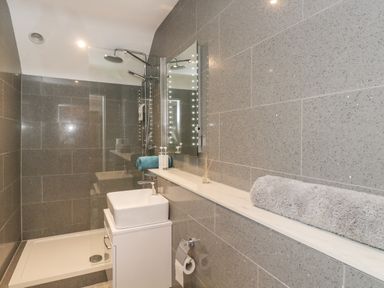 A bathroom with a shower area sink mirror and towels at Upper Annex Quemerford