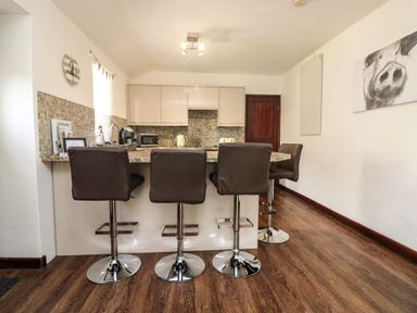 A kitchen with four bar stools at a counter and mosaic tile backsplash at The Old Piggeries in Gulval near Penzance