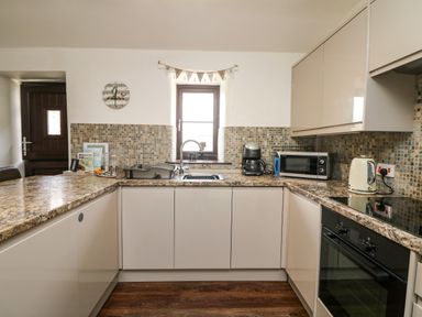 A kitchen with a sink microwave coffee maker kettle and oven at The Old Piggeries in Gulval near Penzance