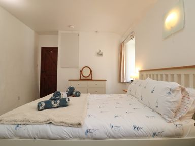 A bedroom with a double bed featuring ship-themed bedding and rolled towels on a blanket at The Old Piggeries in Gulval near Penzance