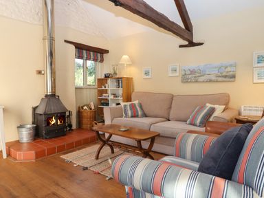 A living room with a wood burning stove sofa armchair coffee table and bookshelf at The Calf Pen in Colyton