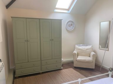 A bedroom with a wardrobe and an armchair at The Calf Pen in Colyton