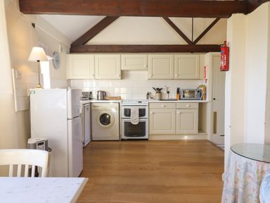 A kitchen with white cabinets appliances and wooden floor at The Bull Pen in Colyton