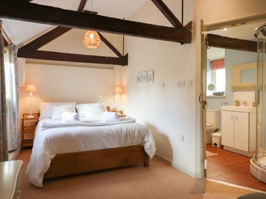 A bedroom with a double bed between two lamps and a visible bathroom with shower at The Bull Pen in Colyton