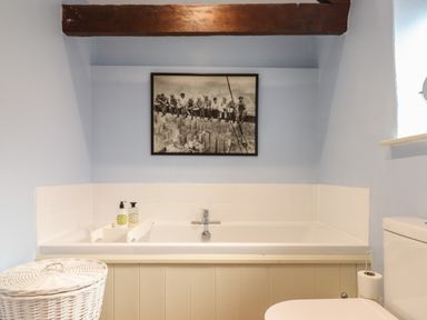 A bathroom with a bathtub soap dispenser toilet and a black and white photo above the tub at The Bull Pen in Colyton