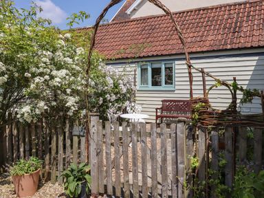 A garden area with a wooden fence a small table and chairs and a bench outside a building at The Bull Pen in Colyton