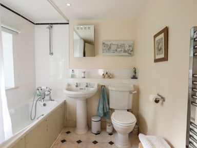 A bathroom with a bathtub sink toilet mirror and wall art at The Hay Loft in Colyton