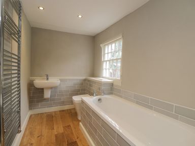 A bathroom with a bathtub toilet sink window and towel radiator at The Old Bakehouse in Avebury