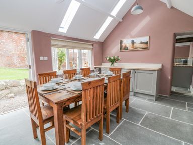 A dining room with a wooden table set with plates and glasses at The Old Bakehouse in Avebury