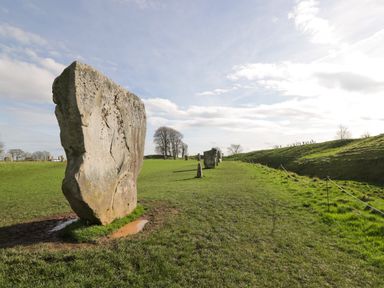 A grassy field with standing stones and a cloudy sky at The Old Bakehouse in Avebury