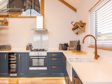 A kitchen with blue cabinets a built in oven a gas stove and a copper faucet at Stags Mount Thornton Dale