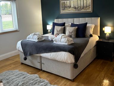 A bedroom with a bed with pillows and towels on a wooden floor at Stags Mount in Thornton Dale