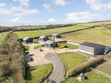 A group of four houses with a driveway and gates surrounded by fields at Stags Mount in Thornton Dale