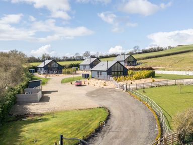 A group of modern houses with large windows on a gravel driveway in a rural setting at Stags Mount in Thornton Dale