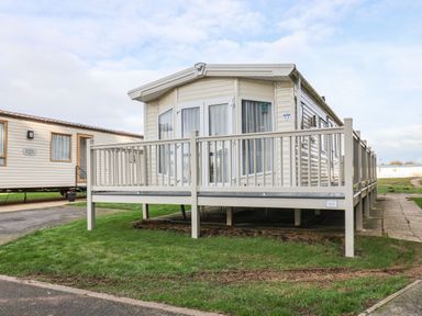 A mobile home with a porch and railing on grass next to a paved path at Forest Star in Cayton