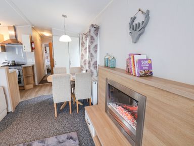 A dining area with a table and four chairs next to a kitchen and an electric fireplace at Forest Star in Cayton