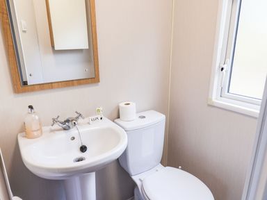 A bathroom with a sink, toilet, mirror, and a window at Forest Star in Cayton