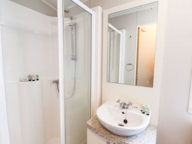A bathroom with a shower enclosure and a sink with a mirror above at Forest Star in Cayton