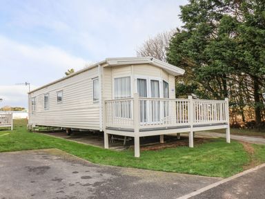 A mobile home with a small deck on grass near trees at Forest Star in Cayton