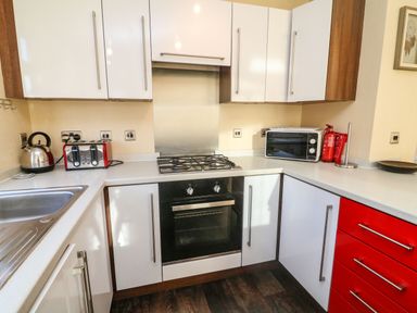 A kitchen with a gas stove oven microwave red toaster kettle and fire extinguisher at Dream Catcher Lodge in Carnforth