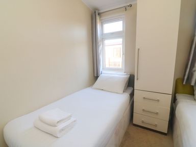 A small bedroom with a single bed white pillows towels and a wardrobe next to a window at Dream Catcher Lodge in Carnforth