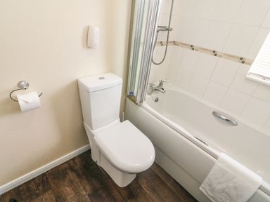 A bathroom with a toilet bathtub shower and a towel at Dream Catcher Lodge in Carnforth
