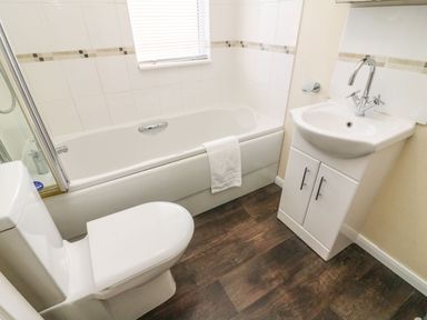 A bathroom with a toilet sink with cabinet and bathtub with towel at Dream Catcher Lodge in Carnforth