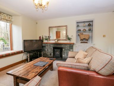 A living room with a sofa coffee table television and fireplace at Scandale Bridge Cottage in Ambleside
