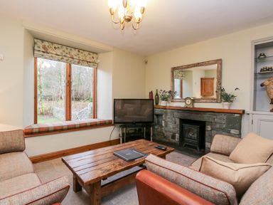 A living room with sofas coffee table television and fireplace at Scandale Bridge Cottage in Ambleside