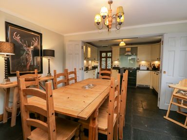 A dining room with a wooden table and chairs adjacent to a kitchen area at Scandale Bridge Cottage in Ambleside