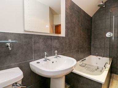 A bathroom with a pedestal sink toilet bathtub and a glass shower screen at Scandale Bridge Cottage Ambleside
