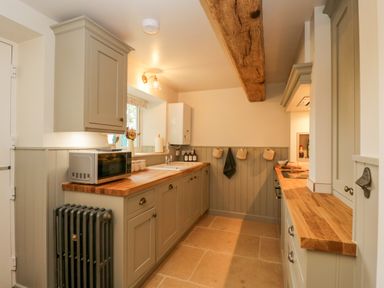 A kitchen with wooden countertops cabinets and a microwave at Thorn Cottage in Fairford