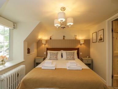 A bedroom with a double bed two bedside tables and a window at Thorn Cottage in Fairford