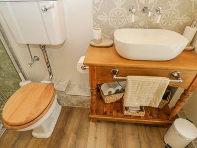 A bathroom with a wooden toilet seat and wooden sink cabinet at Thorn Cottage in Fairford