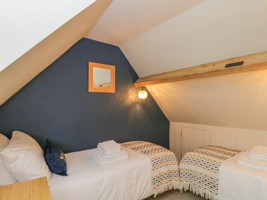 A small bedroom with two single beds and a wooden beam at Thorn Cottage in Fairford