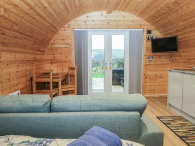 An interior view of a pod with a sofa and dining area at Holly in Ulverston