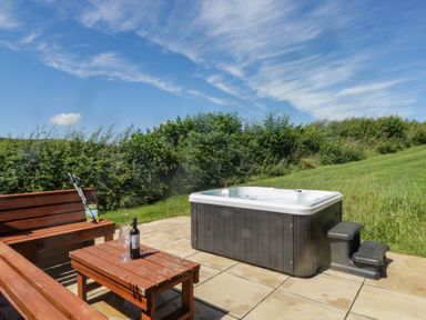 An outdoor area with a hot tub and sitting furniture at Holly in Ulverston