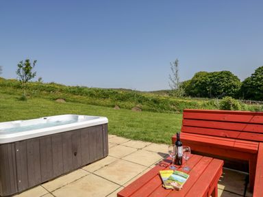 An outdoor area with a hot tub and a red bench at Willow in Ulverston