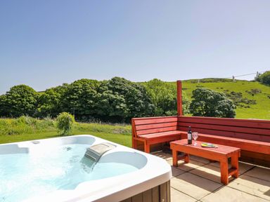 An outdoor patio with a hot tub and seating area at Willow in Ulverston