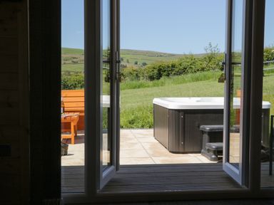 An open door leading to a patio with a hot tub and wooden bench outside at Oak in Ulverston