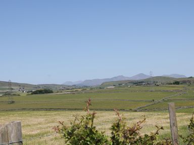 A rural landscape with green fields stone fences and distant hills at Rowan in Ulverston