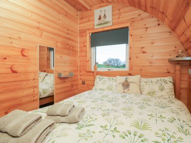 A bedroom with a bed and mirror at Rowan in Ulverston