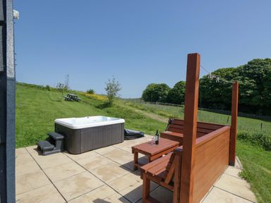 An outdoor area with a hot tub and wooden seating at Cherry in Ulverston