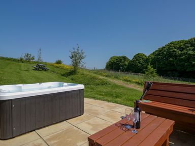 An outdoor area with a hot tub and wooden bench at Cherry in Ulverston