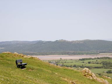 A bench on a hillside overlooking fields and water at Cherry in Ulverston