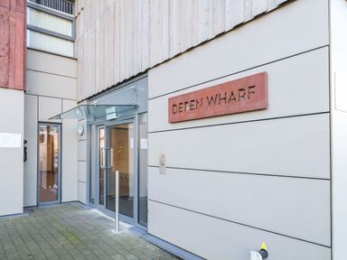 Entrance to a building with glass double doors and a sign reading deten wharf on the wall at Woodbridge Penthouse in Woodbridge