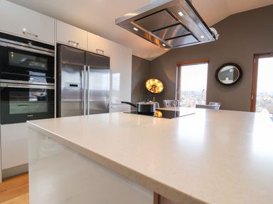 A kitchen with a large island countertop stainless steel double door refrigerator built in ovens and a pot on an induction stove at Woodbridge Penthouse in Woodbridge